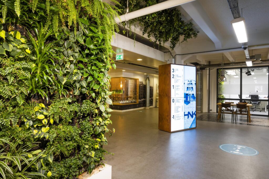 Modern office lobby with a vertical green wall, digital floor directory, and glass meeting rooms at Van Diemenstraat.